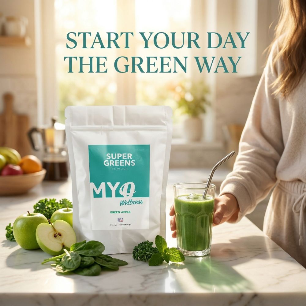 Person holding a glass of green smoothie next to a package of MYOwellness organic superfoods powder on a kitchen counter.