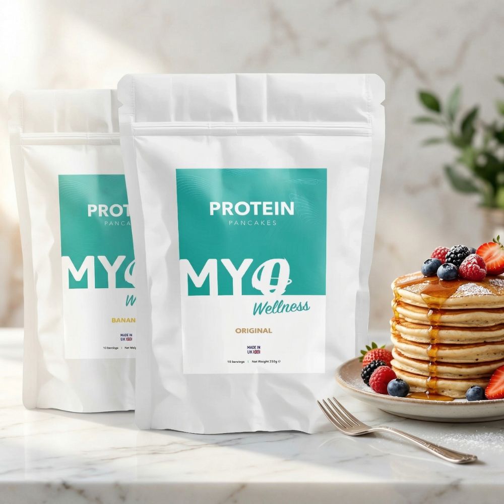 Two packages of MYOwellness protein powder on a marble surface with pancakes and berries.