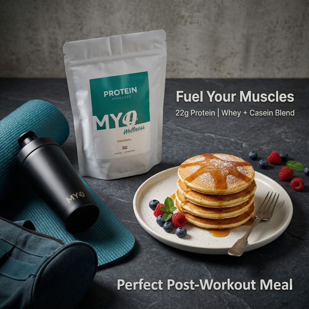Protein pancake powder mix package with pancakes and berries on a plate, gym bag, and water bottle on a dark surface.